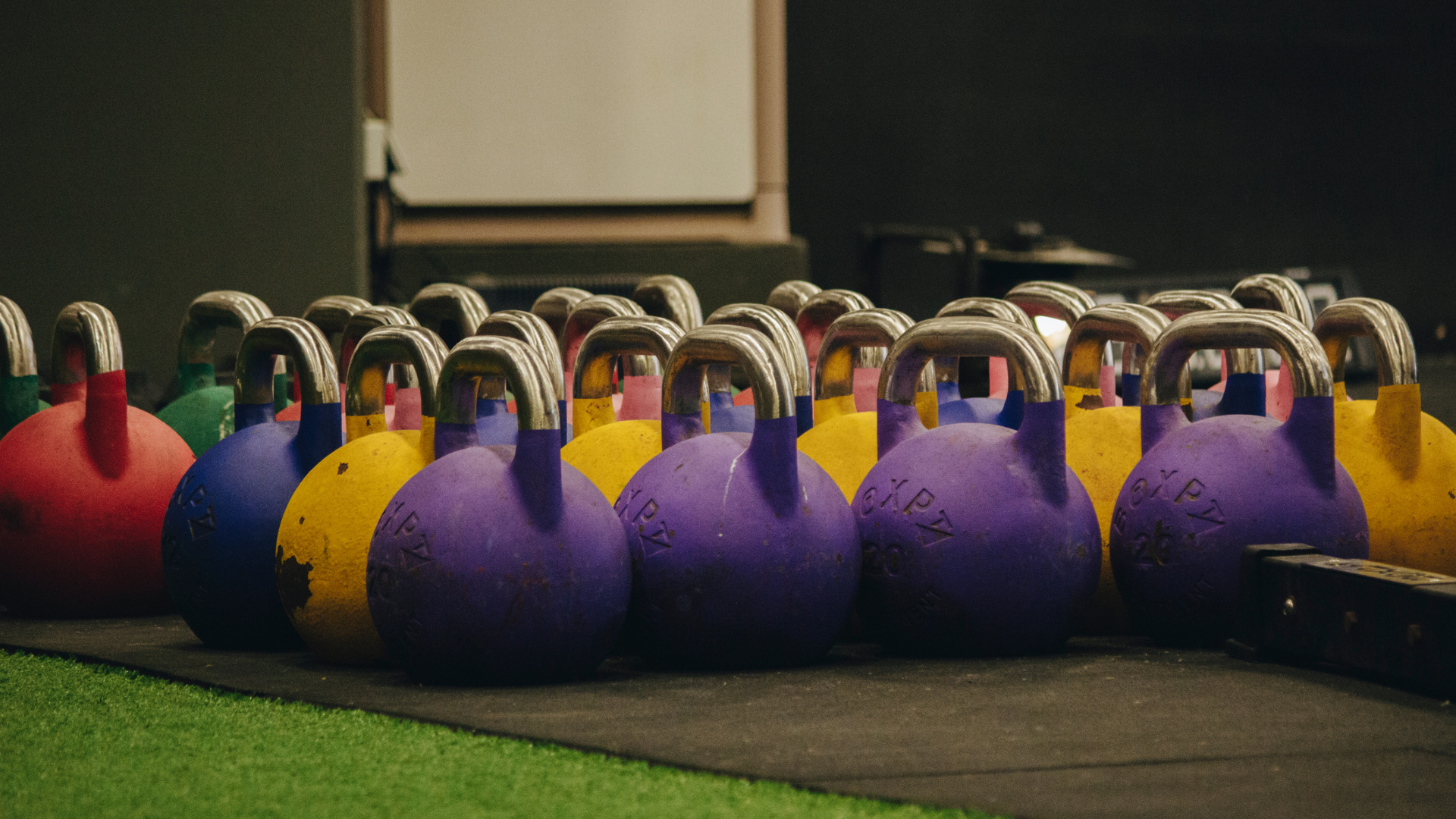 image of a gym setting focused on the colourful collection of kettlebells
