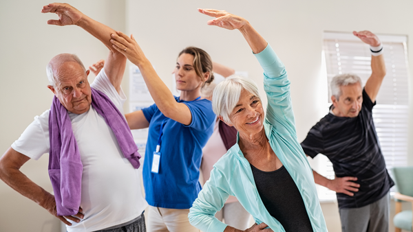 3 older people doing exercise with a medical instructor assisting the male client on the left hand side
