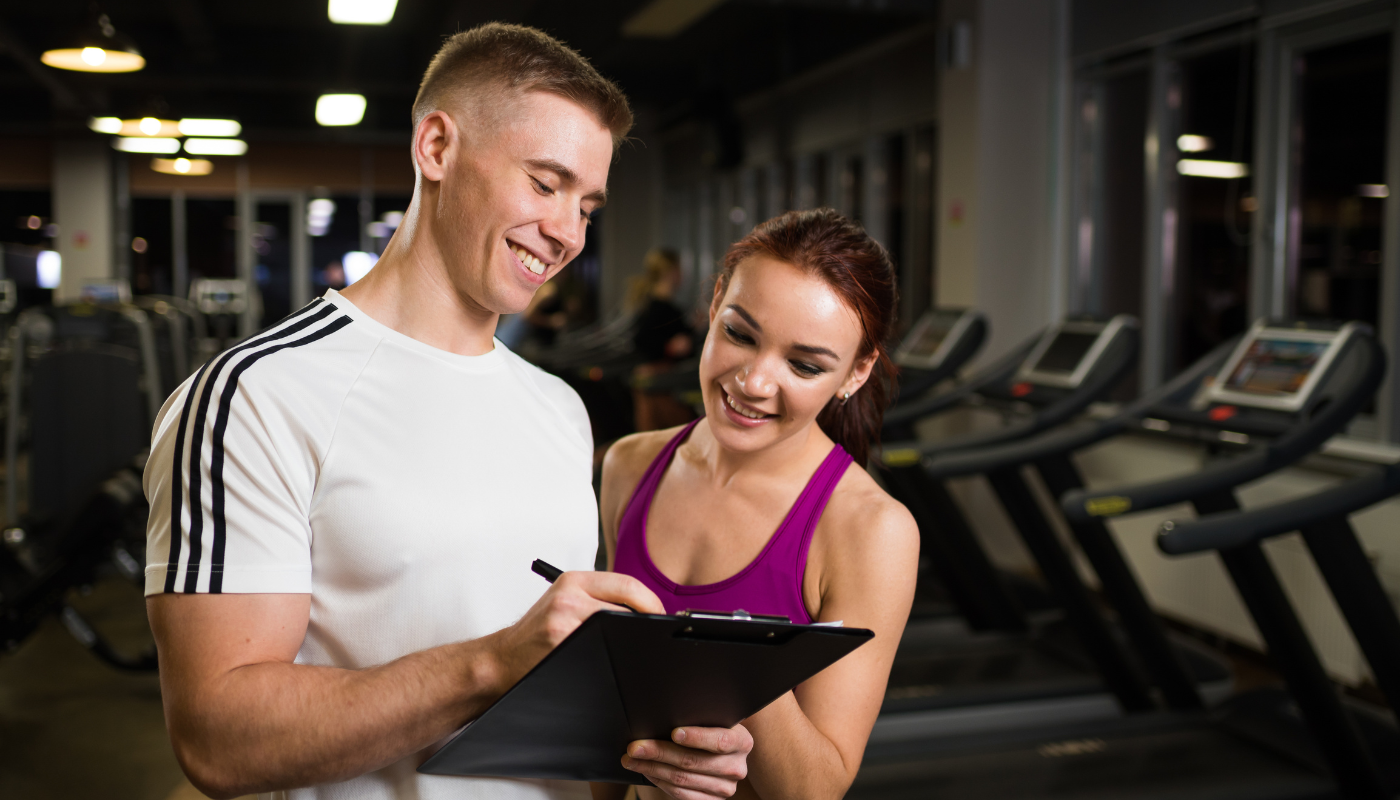 personal trainer and client looking at a clipboard smiling