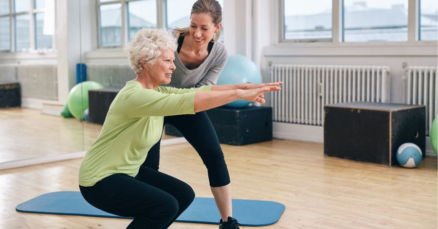 Trainer supporting an older client through a squat